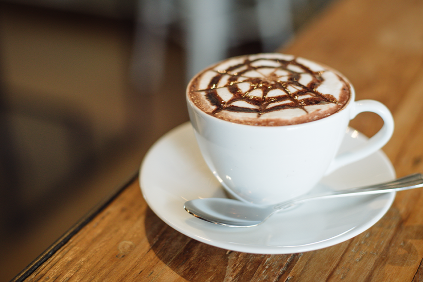 mocha in a mug on a saucer with whipped cream and chocolate syrup